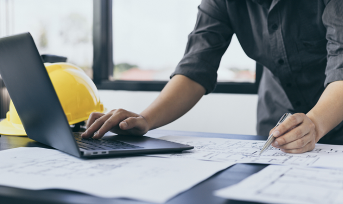 PCを操作しながら資料作成している人の画像