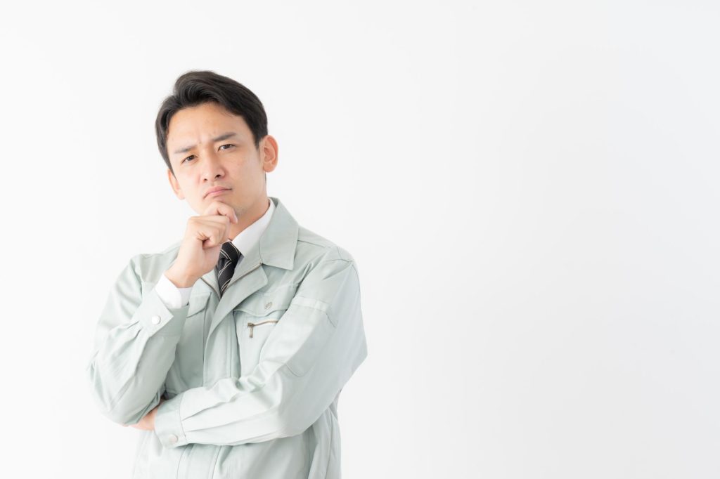 作業着姿で考えている人の画像